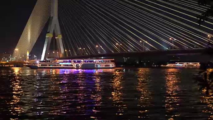 在电缆桥下的河上部署有灯光的休闲船。第1部分
