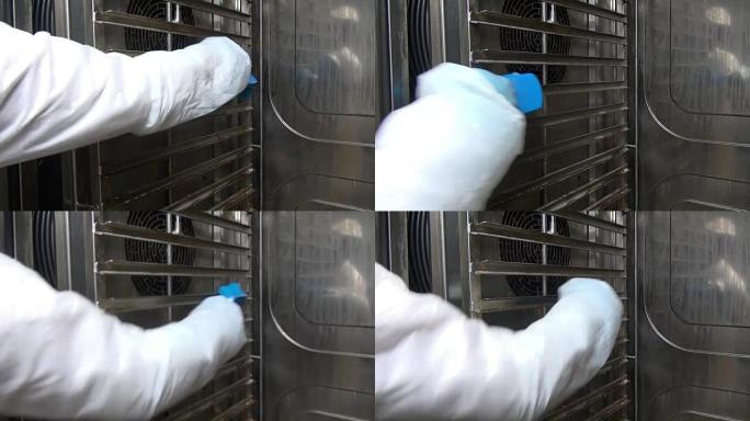 工人手中的蓝色刷子清洁洗涤工业烤箱。