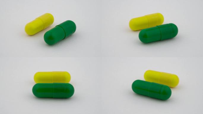 两个硬淀粉胶囊在转盘上旋转。黄色和绿色。孤立在白色背景上。特写宏。