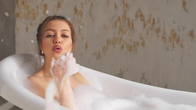 年轻愉快的女孩在浴室玩泡沫