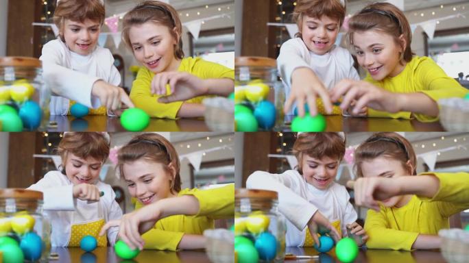 复活节周日家庭节日传统。两个高加索快乐的兄弟姐妹孩子，兔子耳朵在玩多色的复活节彩绘鸡蛋。一起玩得开心