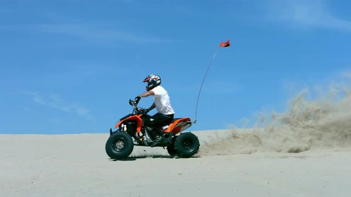 男子骑着四轮摩托穿越沙滩，慢动作