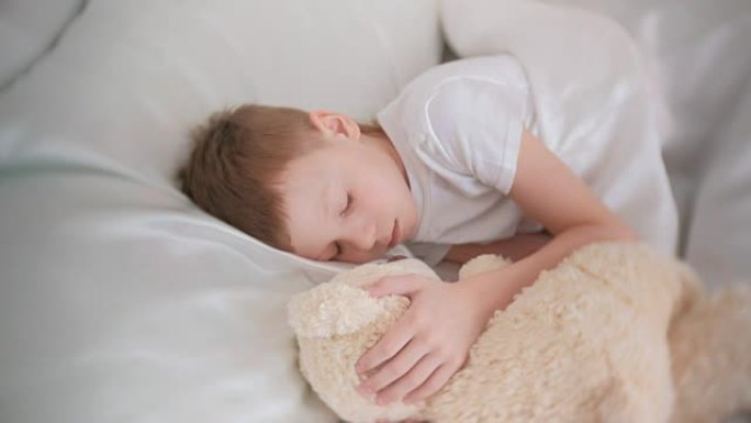 七岁男孩抱着玩具熊睡着了。
