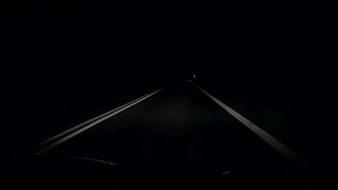 在黑色黑暗的夜晚，在没有路标的道路上快速行驶。另一条车道上的卡车