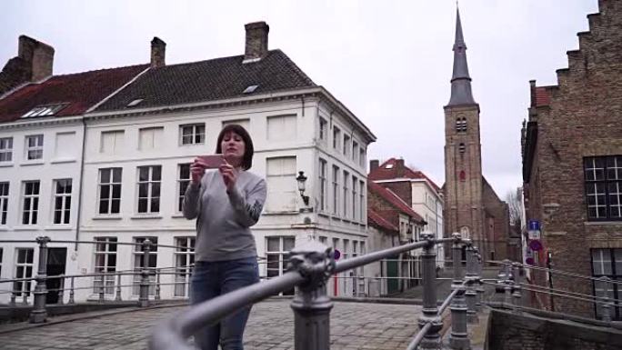 女游客在比利时布鲁日的智能手机上拍照