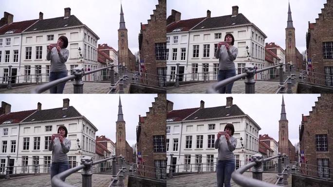 女游客在比利时布鲁日的智能手机上拍照