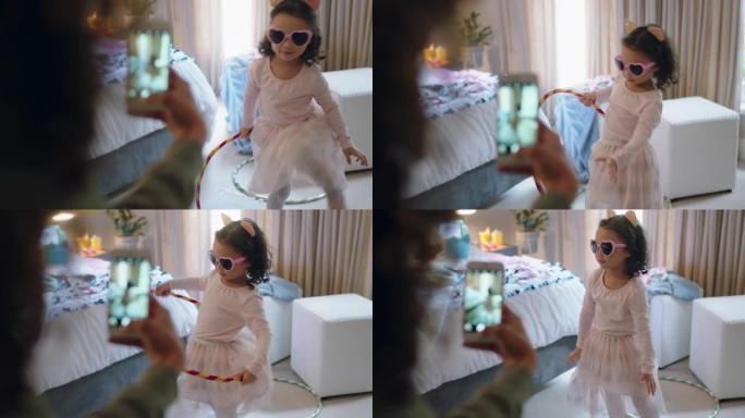 快乐的小女孩在卧室里玩呼啦圈跳舞妈妈用社交媒体上的智能手机分享拍照