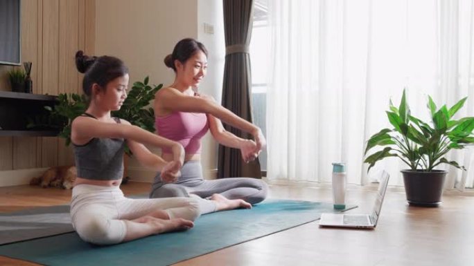 笔记本电脑视频会议上的虚拟瑜伽课程将亚洲母亲和女儿的身心结合在一起