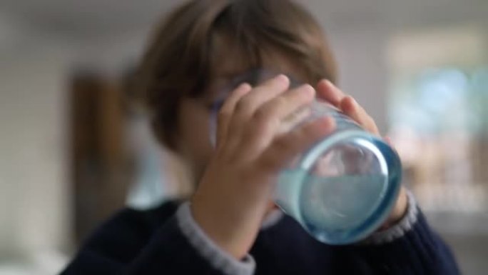 一个口渴的孩子在室内喝水。给自己补水的小男孩