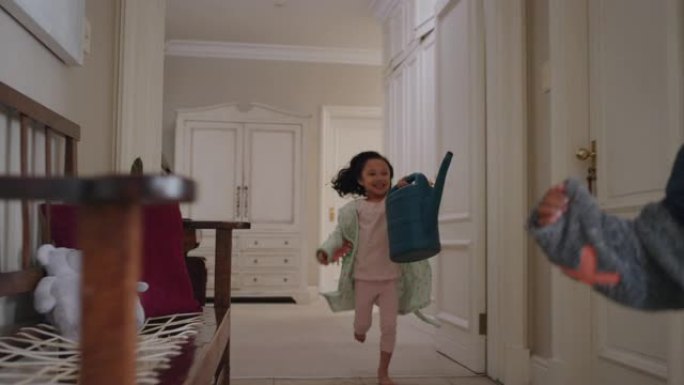 淘气的孩子在房子里跑可爱的小女孩微笑着用浇水来追逐她的哥哥，兴奋的孩子享受童年游戏，周末早上穿着睡衣