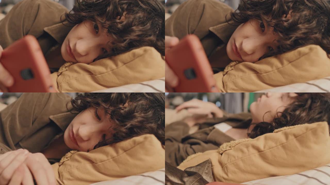 悲伤的卷发女孩躺在床上检查她的手机，特写