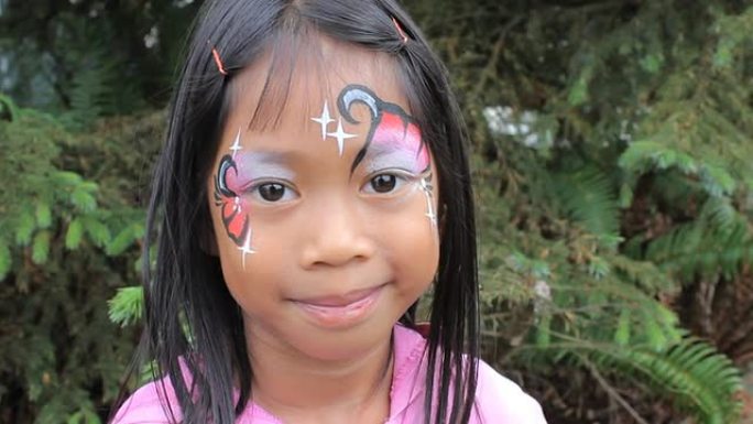 可爱的亚洲女孩炫耀她的面部油漆设计