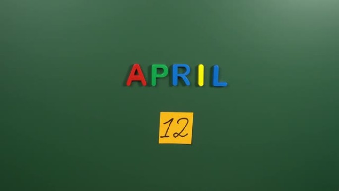 4月12日日历日用手在学校董事会上贴一张贴纸。12 4月日期。4月的第十二天。第12个日期编号。12