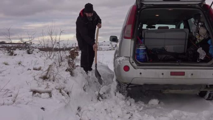 男子在汽车附近用铲子挖雪