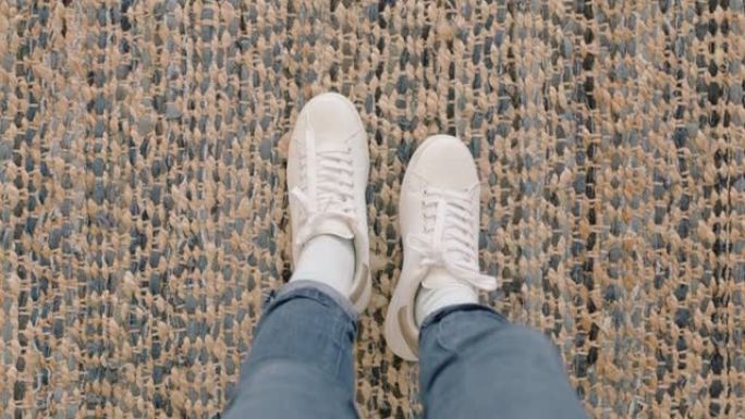 顶视图女人穿着白鞋，站在地毯上享受时尚的新鞋