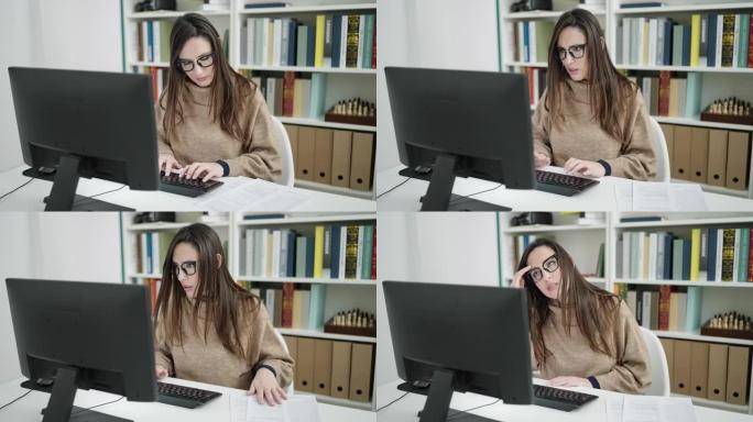 美丽的西班牙裔女学生在图书馆大学使用计算机阅读文档