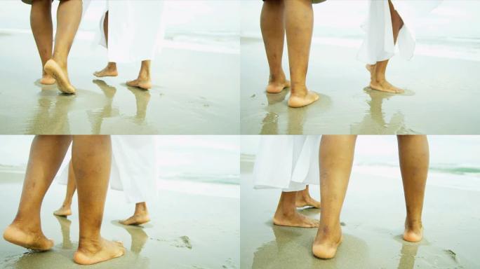 腿老年民族夫妇赤脚散步海滩