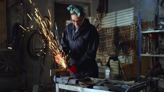 专业女焊工在维修车间用角磨机打磨金属，火花四溅。穿着工作服和护目镜的年轻女机械师在做维修工作