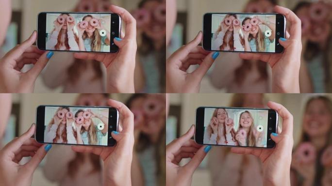 有趣的少女与甜甜圈朋友在社交媒体上使用智能手机分享拍照，享受周末愚蠢的乐趣