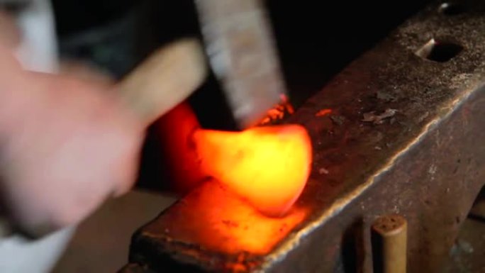 一位钢铁大师撞击高热金属并对其进行整形的特写镜头视频
