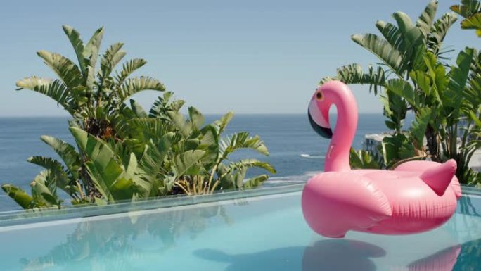 豪华酒店度假村游泳池里的粉色火烈鸟充气游泳管，阳光明媚的暑假可以看到美丽的海景4k镜头