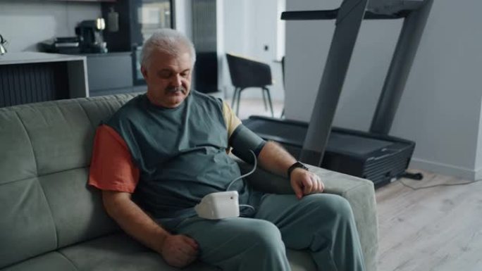患有高血压疾病的高级男子在家锻炼后通过数字小工具检查血压