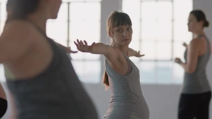 瑜伽课健康孕妇练习战士姿势享受日出时工作室教练的集体体能锻炼