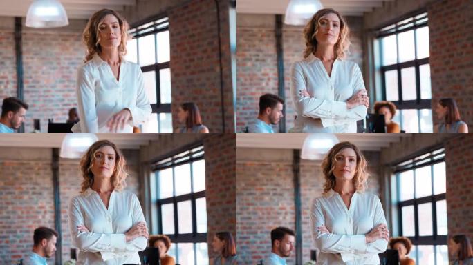 严肃的女商人在办公室的肖像，同事在后台工作