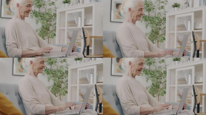 退休女士的慢动作与笔记本电脑一起工作，在家中使用无线技术打字微笑