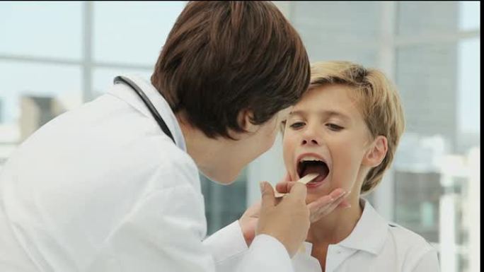 医生看着一个小男孩的扁桃体