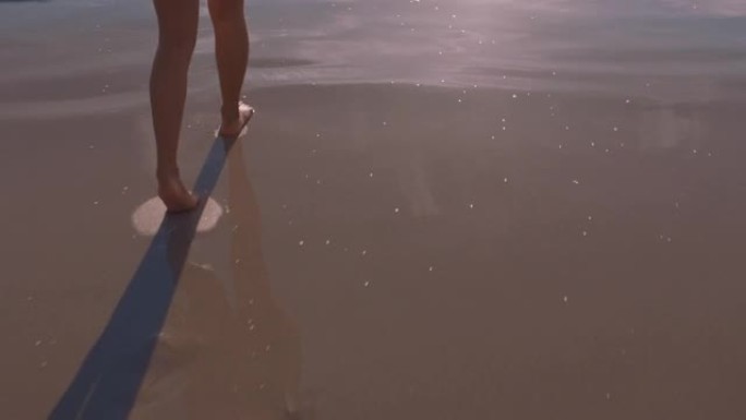 近距离的女人脚走在海滩上日落享受海浪轻轻飞溅暑假女游客