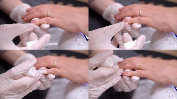 专业美甲师在无菌手套上涂抹治疗性指甲油在客户的指甲板上，女性在美容院用透明抛光剂涂指甲，固化修指甲程
