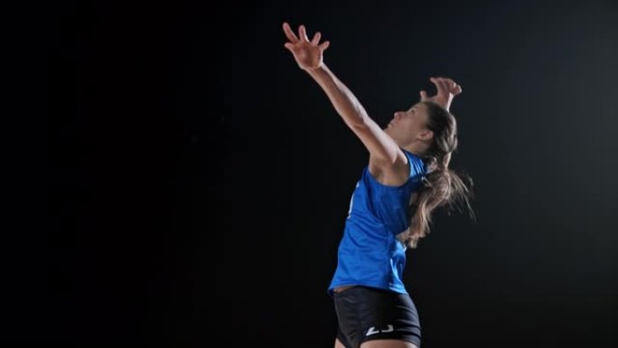 身穿蓝色球衣的SLO MO女子排球运动员跳球击球