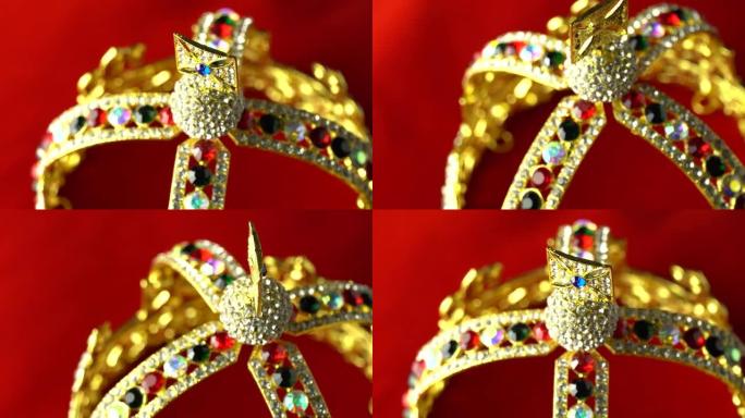 Extreme macro close将焦点转移到红色柔软天鹅绒皇家礼仪枕头上的黄金和珠宝钻石王冠上
