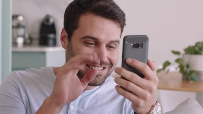 快乐的年轻人用智能手机视频聊天，对着婴儿微笑的父亲在家里享受手机聊天