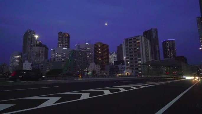 黄昏时的城市景观。高层公寓区的夜晚，月亮和过往的汽车