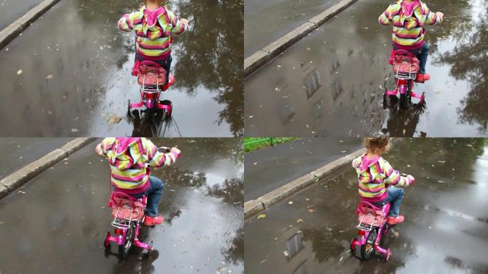 小女孩在水坑湿沥青上踩踏板
