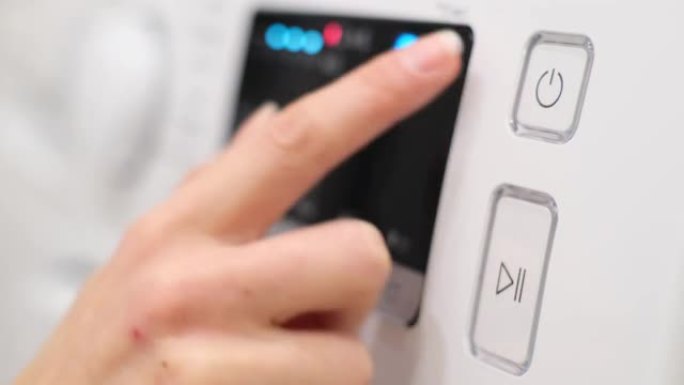 一个男人的手打开洗衣机的特写镜头。用手指推动开关启动洗衣机。