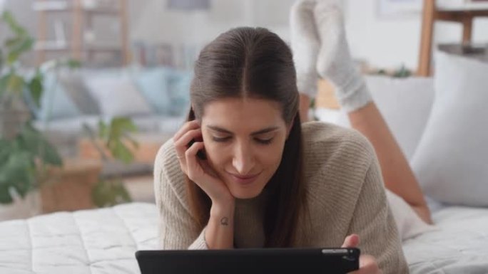 美丽的女人使用平板电脑在床上放松浏览互联网输入社交媒体消息在线移动触摸屏技术4k镜头