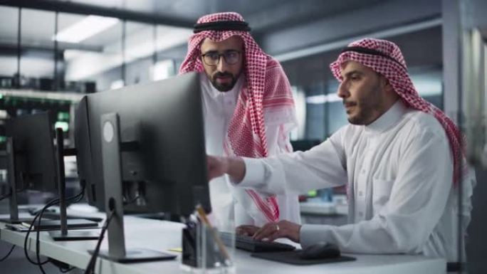 两名中东同事在忙于在线业务项目时进行了交谈。年轻的阿拉伯开发商与穆斯林项目经理交谈。技术实验室中的团