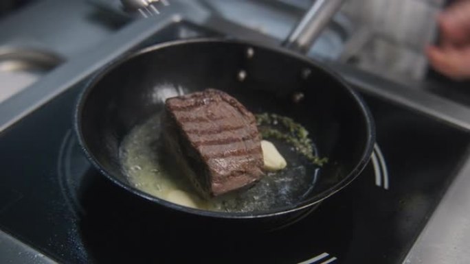 厨师用迷迭香在锅上炸猪肉