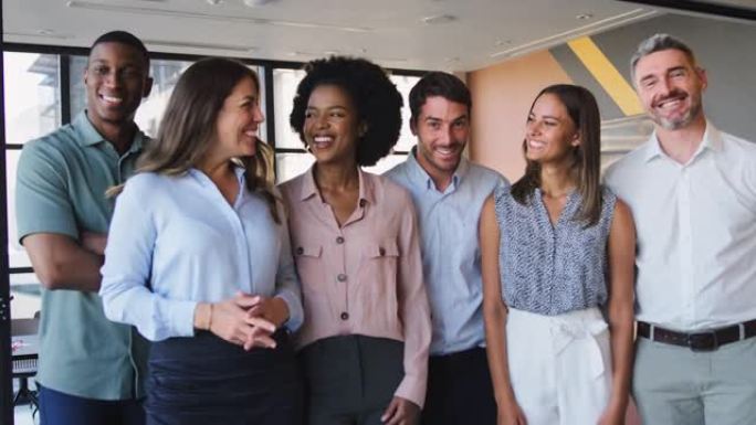 微笑的多元文化商业团队站在现代办公室的肖像