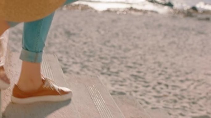 靠近脚女人走下台阶在海滩上享受温暖的阳光灿烂的日子无忧无虑的女孩探索暑假生活方式