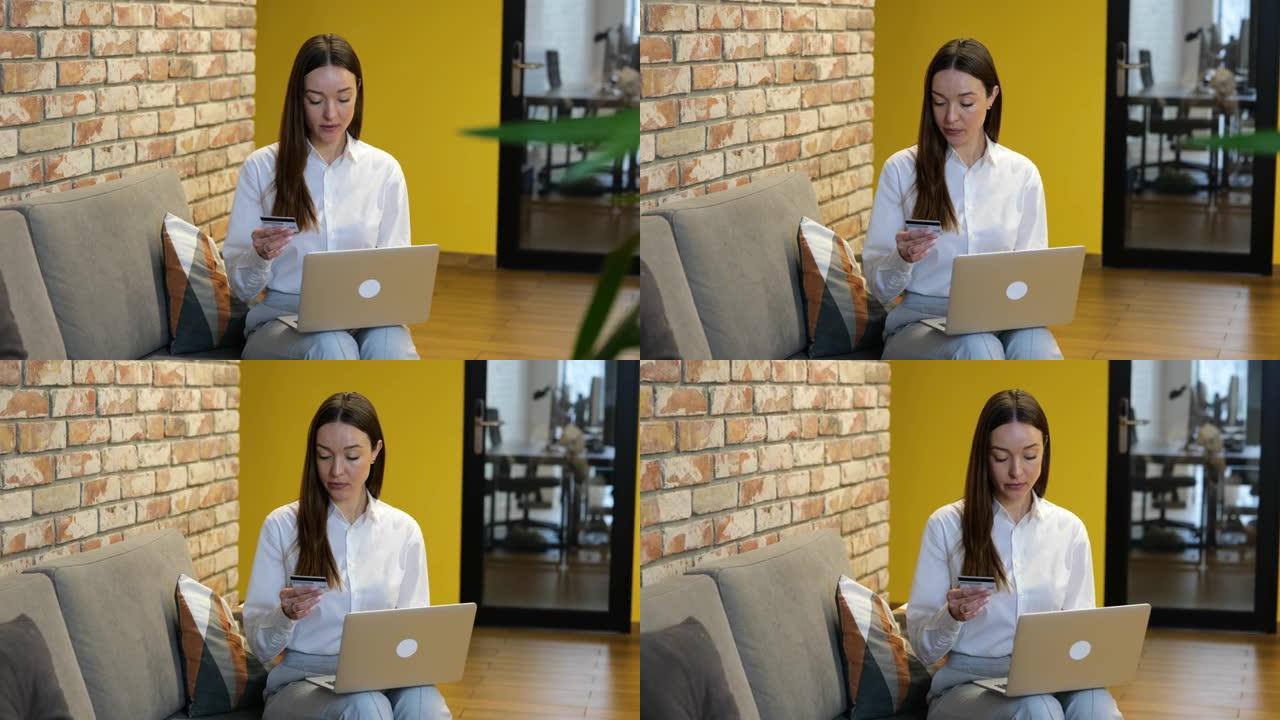慢动作视频白衬衫和灰色裤子的白人美女正坐在灰色沙发上，在电脑上工作。