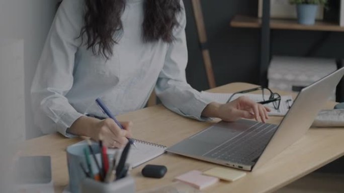 雄心勃勃的亚洲商务女士在办公室用笔记本电脑打字和笔记本电脑写信息的肖像