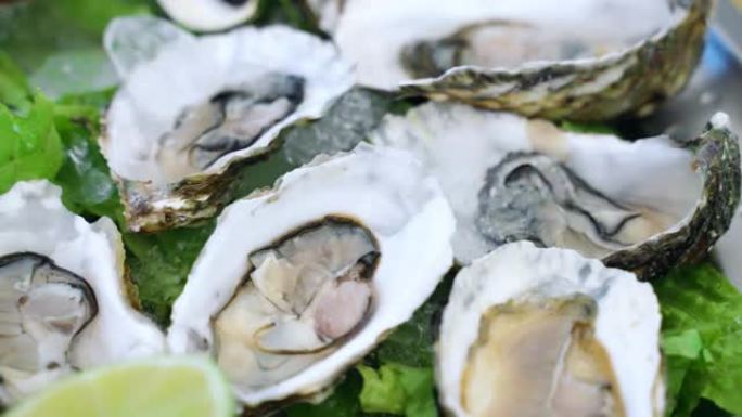 美味的新鲜牡蛎熟食店配以冰和柠檬片，富含维生素和omega-3的昂贵海鲜美食，健康的地中海饮食，软体
