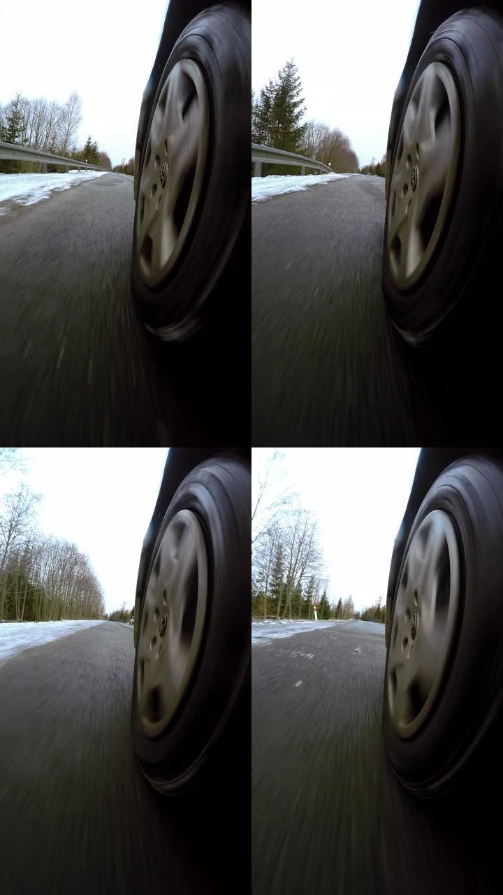 特写车轮从汽车视点下旋转。在积雪覆盖的冬季道路上驾驶汽车垂直视频