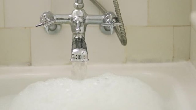 浴室里流动的水、水龙头和泡泡浴，用于清洗、放松和清洁，以实现自我护理和安宁。家用镀铬水龙头，浴缸中有