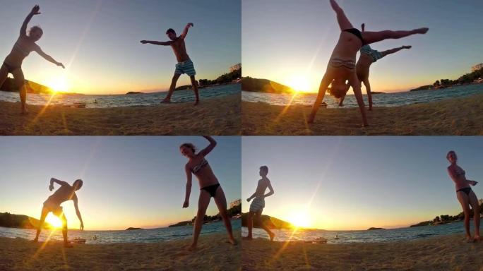 两个青少年在日落海滩慢动作做侧翻