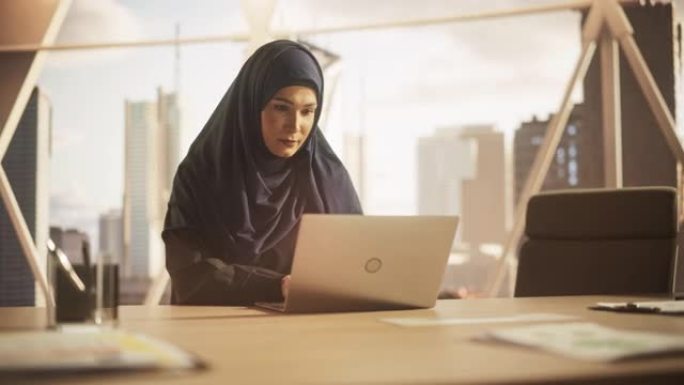 授权一位戴着头巾的穆斯林女商人的肖像，在金融科技初创公司的笔记本电脑上工作。阿拉伯金融分析师在新兴的